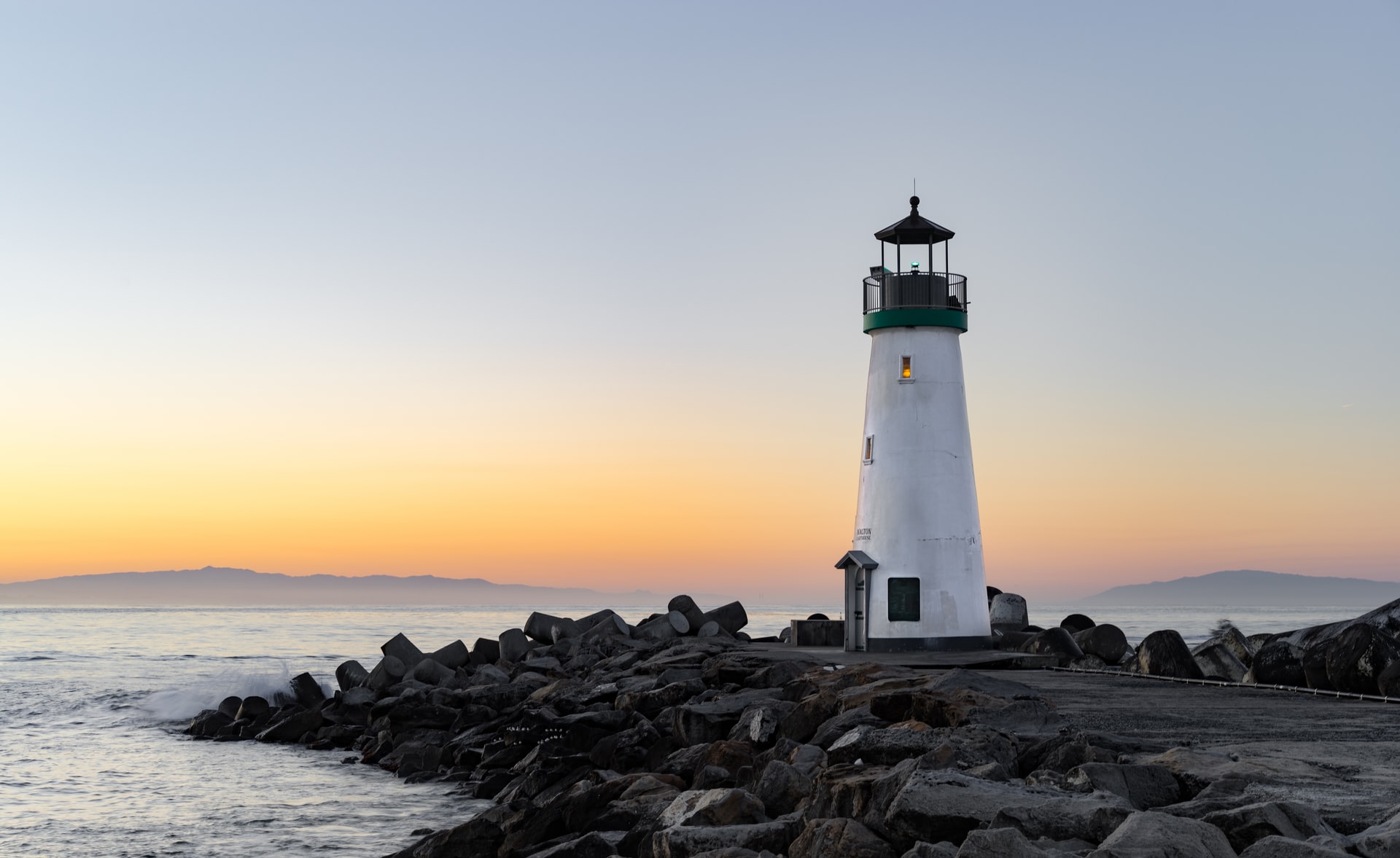 Light house on rockbed against sunset